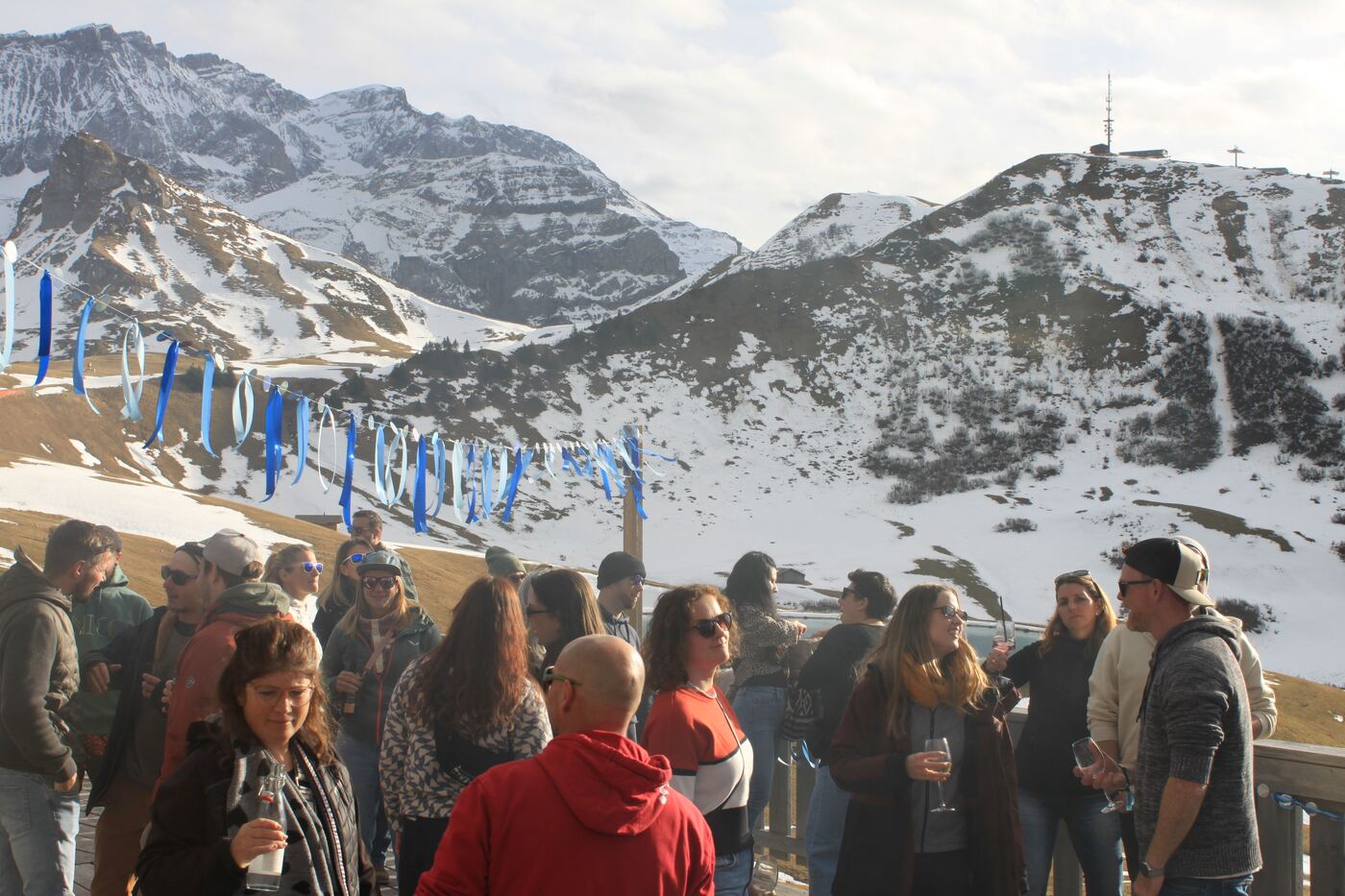 Crowd at the Daydance on Hahnenmoos with snowy mountains behind