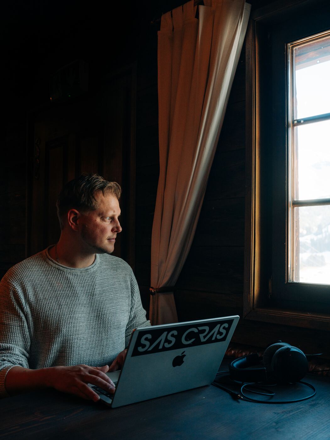 Sas Cras working on a laptop by a window